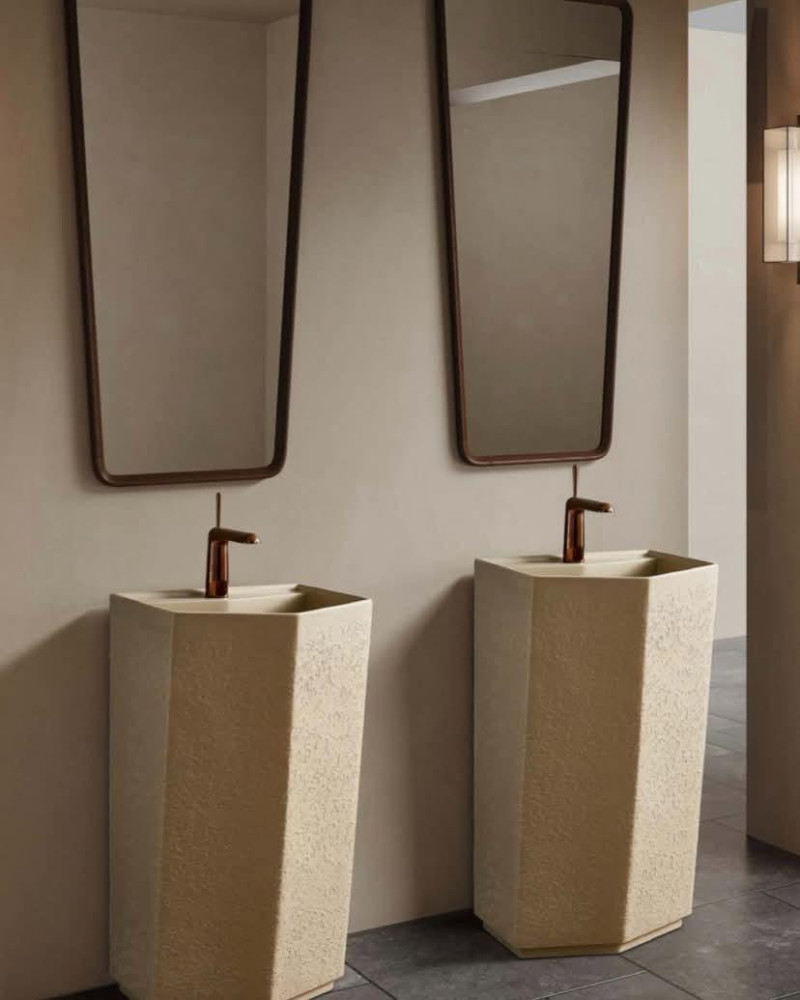 pair of freestanding pedestal wash basins with a textured, off-white ceramic finish and modern faucets